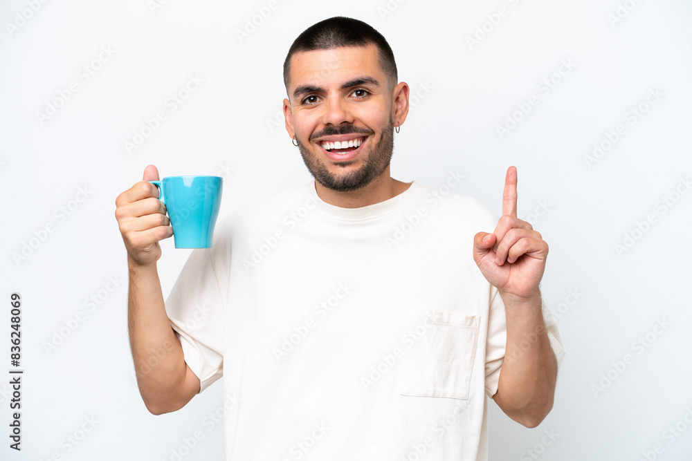 Young caucasian man holding cup of coffee isolated white background pointing up a great idea Young caucasian man holding cup of coffee isolated white background pointing up a great idea