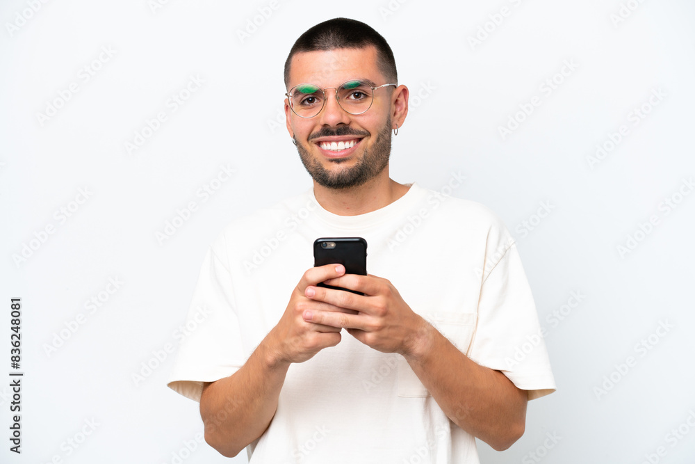Young caucasian man isolated on white background looking at the camera and smiling while using the mobile Young caucasian man isolated on white background looking at the camera and smiling while using the mobile