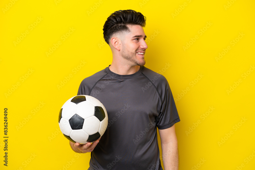 Handsome young football player man isolated on yellow background laughing in lateral position Handsome young football player man isolated on yellow background laughing in lateral position