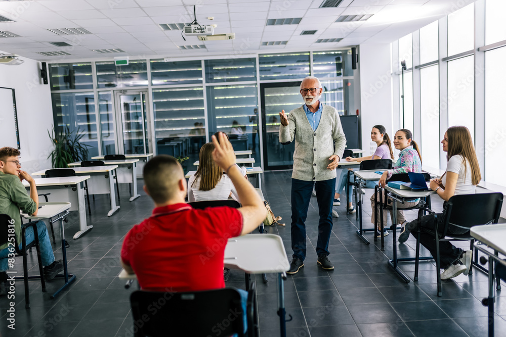Teacher calling on student with raised hands in education classroom Teacher calling on student with raised hands in education classroom