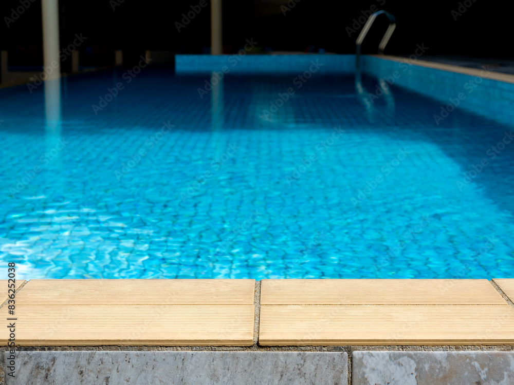 Summer pool background. Empty space on the pool edge, stone tiles and blurred swimming pool in tropical resort, summer background for display or montage your products.