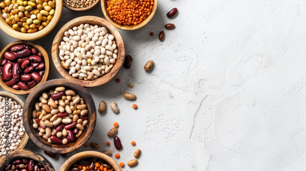 Assorted varieties of dried beans and legumes in wooden bowls on a white table Top view Plant based sources of protein for vegans with space for text Assorted varieties of dried beans and legumes in wooden bowls on a white table Top view Plant based sources of protein for vegans with space for text