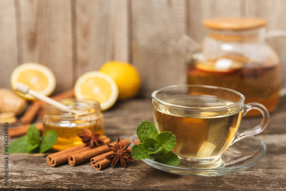 Fragrant hot tea with cinnamon stick and anise on a textured wooden background. A cup of hot tea with honey, lemon, mint and apples. Spicy tea with spices. Immunity tea. Health concept.Copy space. Fragrant hot tea with cinnamon stick and anise on a textured wooden background. A cup of hot tea with honey, lemon, mint and apples. Spicy tea with spices. Immunity tea. Health concept.Copy space.