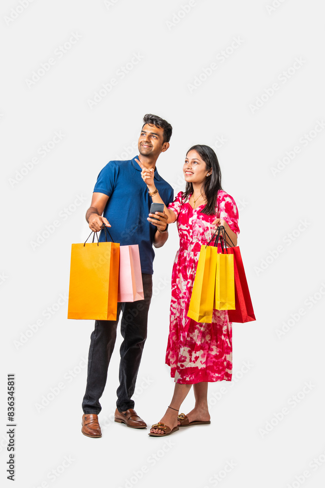 Asian Indian smart and young couple showing shopping bags standi Asian Indian smart and young couple showing shopping bags standi