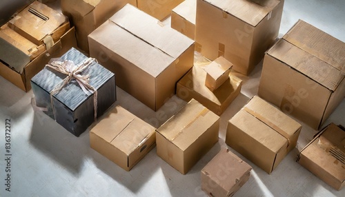  The image shows a collection of cardboard boxes with a ribbon tied around one of them. The boxes are of various sizes and are scattered across the frame.