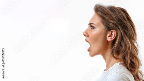 Close up profile of a young Caucasian woman with mouth open wide, shouting. Isolated on white, copy space, aspect ratio 16:9 photo