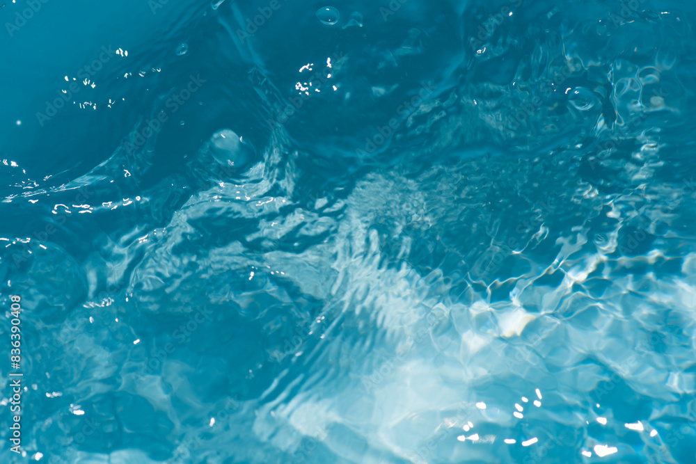 Blue water with ripples on the surface. Defocus blurred transparent blue colored clear calm water surface texture with splashes and bubbles. Water waves with shining pattern texture background. Blue water with ripples on the surface. Defocus blurred transparent blue colored clear calm water surface texture with splashes and bubbles. Water waves with shining pattern texture background.