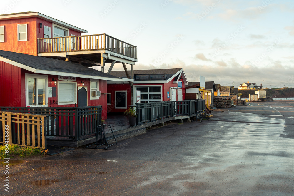 A strip mall with simple 1 and 2 story buildings housing restaurants, vendors and services for local harbour visitors along a paved parking area, Covehead Harbour, Prince Edward Island, Canada A strip mall with simple 1 and 2 story buildings housing restaurants, vendors and services for local harbour visitors along a paved parking area, Covehead Harbour, Prince Edward Island, Canada