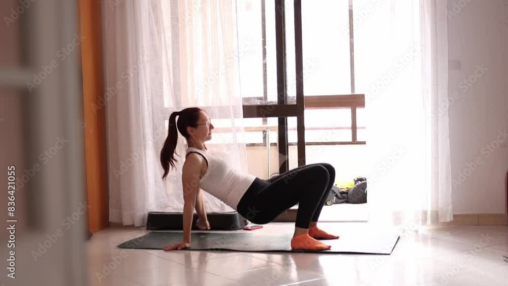 A woman is doing a yoga pose in a room with a window A woman is doing a yoga pose in a room with a window