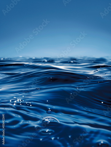 A photo captures the surface of blue water  creating an abstract background with a designated text field. The calm and fluid texture offers a serene and versatile visual.