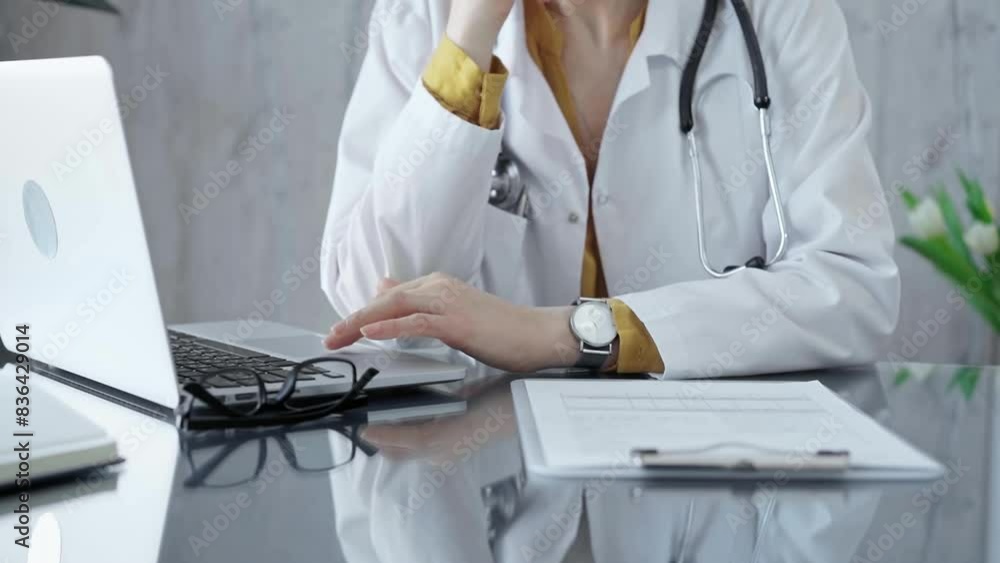 Doctor reviewing medical records on laptop. Close-up of a healthcare professional analyzing patient information on a computer Doctor reviewing medical records on laptop. Close-up of a healthcare professional analyzing patient information on a computer