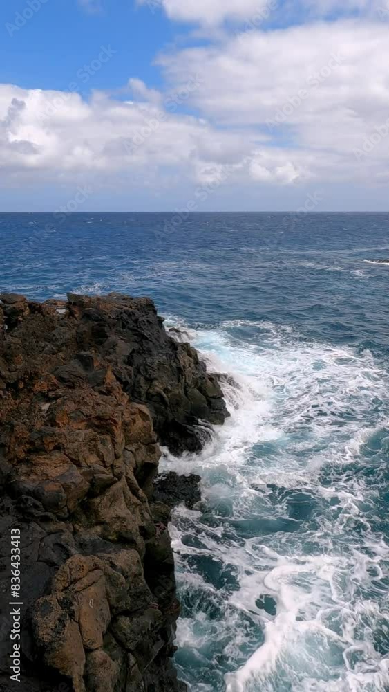 Ocean wave near dark lava rock coast with partly cloudy sky north of Lanzarote in the Canary Islands Ocean wave near dark lava rock coast with partly cloudy sky north of Lanzarote in the Canary Islands