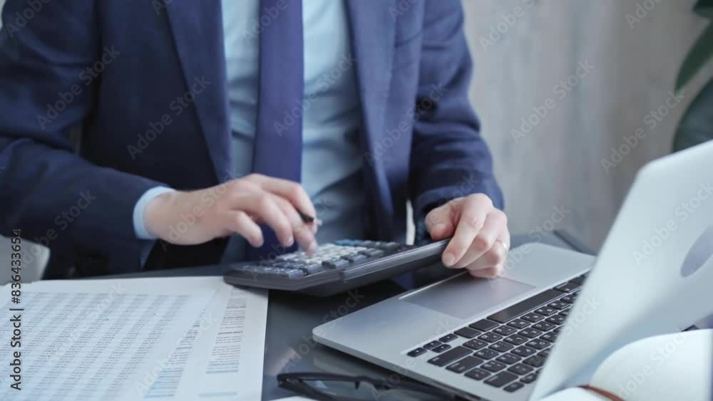Businessman analyzing financial data on laptop and calculator. Close-up of a professional auditor working on financial reports. Business concept Businessman analyzing financial data on laptop and calculator. Close-up of a professional auditor working on financial reports. Business concept