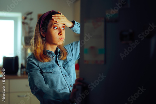 фотографія Woman looking Puzzled into the Fridge Wondering What to Eat