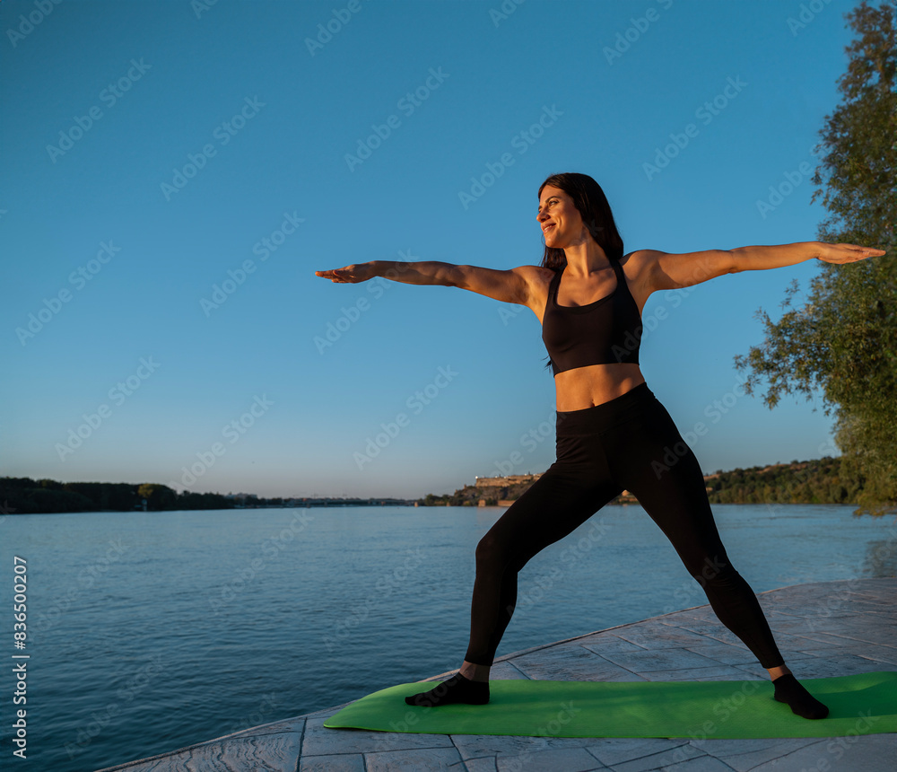 Pretty longa hair brunette in warrior yoga pose by the sea Pretty longa hair brunette in warrior yoga pose by the sea
