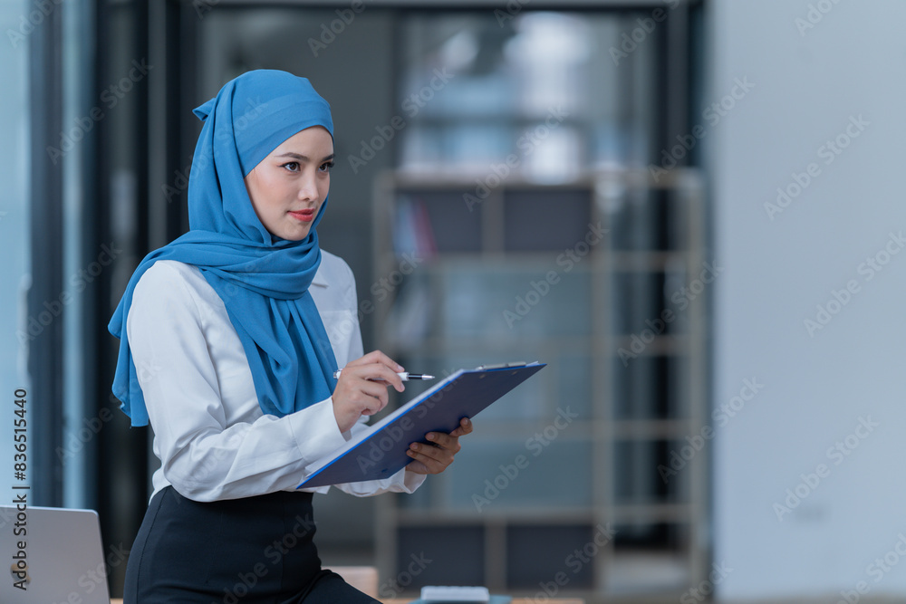 Cheerful muslim lady wear hijab working in the office, using laptop, Side view of smiling arab woman, freelancer typing on laptop, Muslim working woman concept. Cheerful muslim lady wear hijab working in the office, using laptop, Side view of smiling arab woman, freelancer typing on laptop, Muslim working woman concept.
