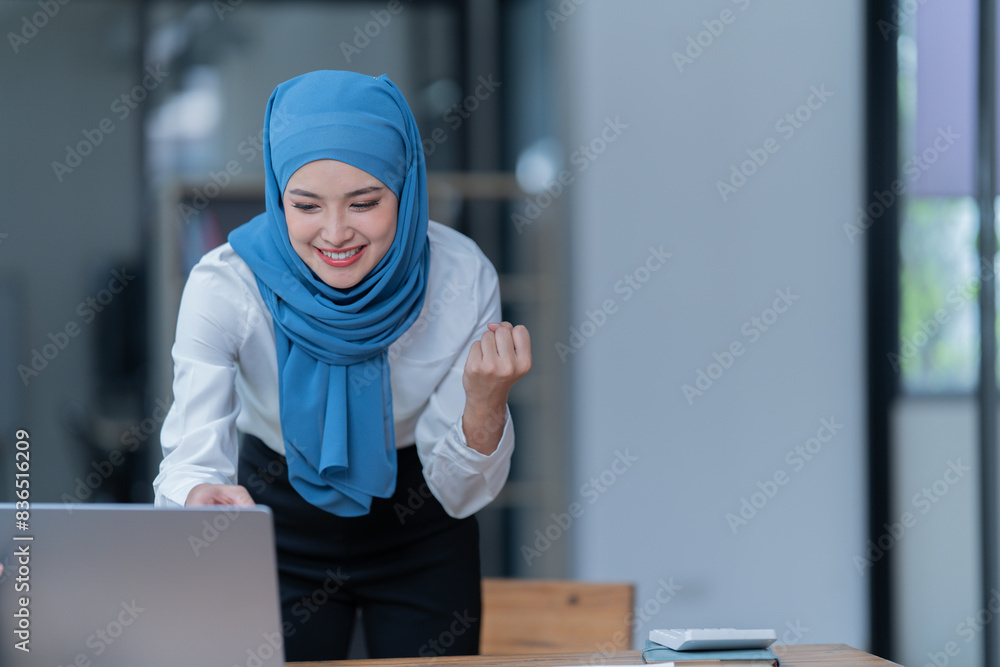 Cheerful muslim lady wear hijab working in the office, using laptop, Side view of smiling arab woman, freelancer typing on laptop, Muslim working woman concept. Cheerful muslim lady wear hijab working in the office, using laptop, Side view of smiling arab woman, freelancer typing on laptop, Muslim working woman concept.