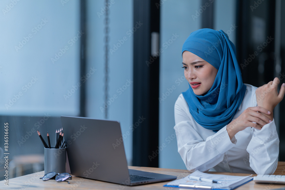A female Arab entrepreneur is diligently working in her office, utilizing her laptop and documents to accomplish her tasks with contentment. A female Arab entrepreneur is diligently working in her office, utilizing her laptop and documents to accomplish her tasks with contentment.