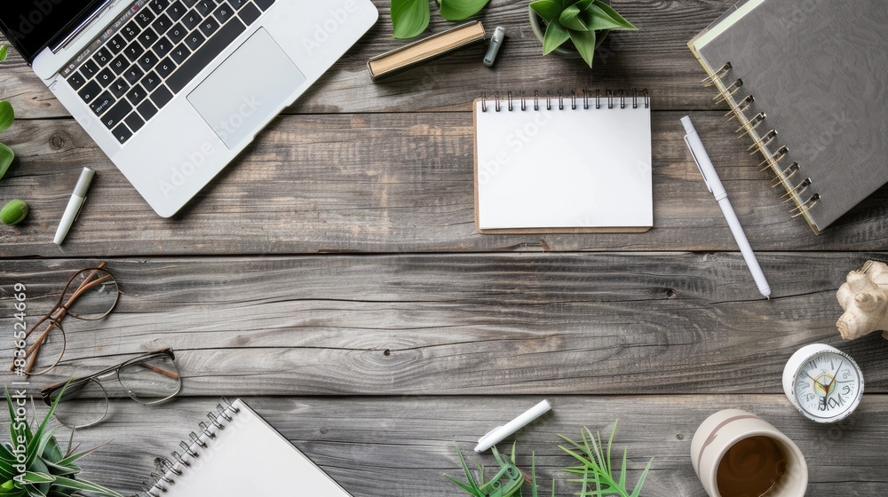Wooden table surface with scattered office supplies and a blank notebook, creating space for text in the center Wooden table surface with scattered office supplies and a blank notebook, creating space for text in the center