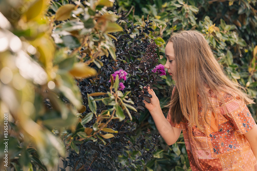 Pre-teen girl smelling crepe myrtle flower in country garden photo