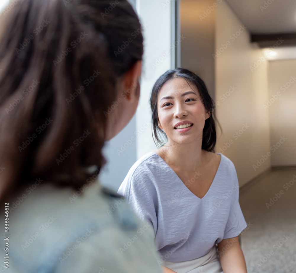 Asian woman smiling while talking to her colleague in an office Asian woman smiling while talking to her colleague in an office