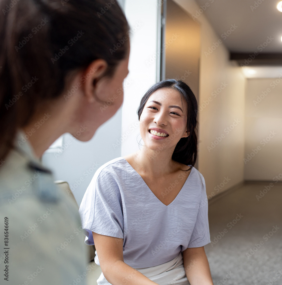 Asian woman smiling while talking to her colleague in an office Asian woman smiling while talking to her colleague in an office