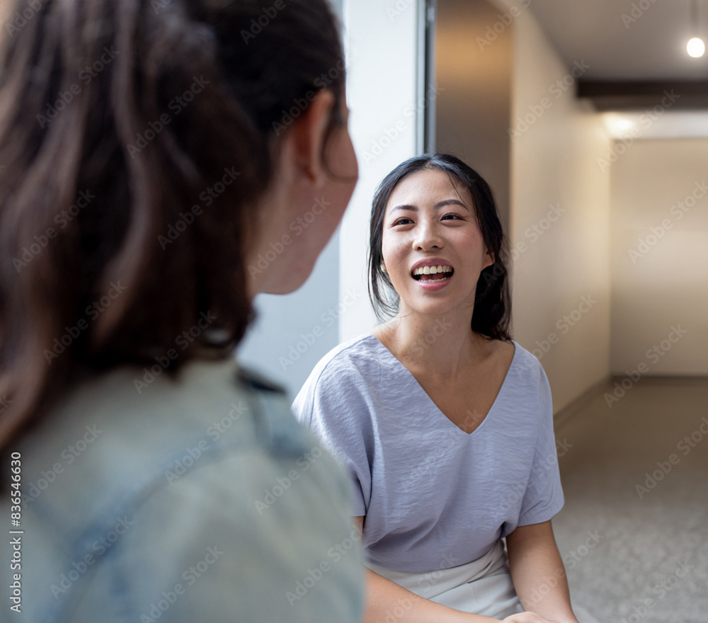 Asian woman smiling while talking to her colleague in an office Asian woman smiling while talking to her colleague in an office