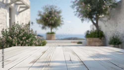 Leerer weißer Holztisch in einem sonnigen mediterranen Garten oder Terrasse mit Blick auf das Meer im unscharfen Hintergrund