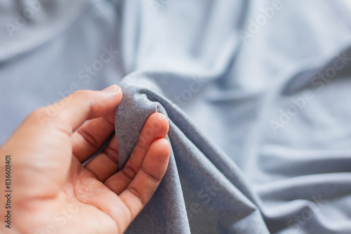 Hands touch the smooth surface of the cloth. The texture of the gray blanket is gentle and soft. Space for text. Cloth handle.