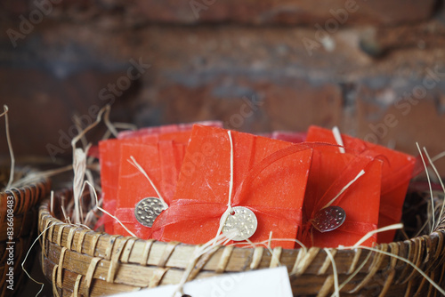 A stack of red color soaps with ribbons in a basket