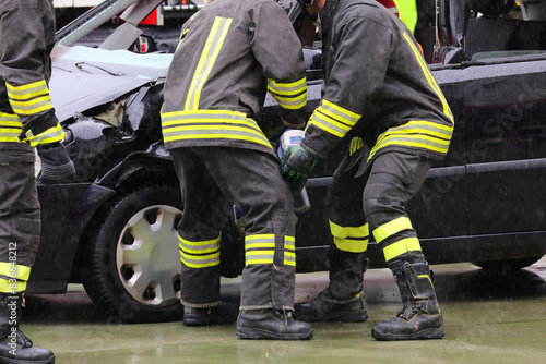 firefighters unhinging the stuck door of a crashed car after the collision using a battery-powered hydraulic shear