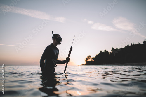 Spearfisherman comes out of the water and holds spear gun photo