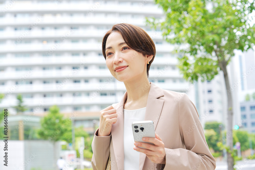 外でスマートフォンを使うビジネスウーマン
