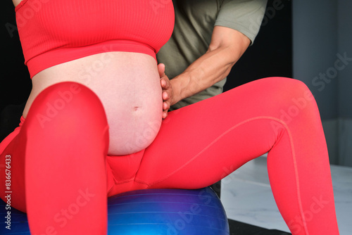 Close up of a pregnant woman doing exercises with personal trainer preparing the body for childbirth. Health and sport during pregnancy.
