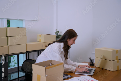 Young female entrepreneur is packing merchandise  at home. © Suney
