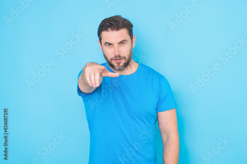 Gesture pointing finger at you. The point you. Happy handsome man pointing finger you away, isolated blue background. Excited man pointing a you great idea. Guy in blue t-shirt pointing finger you.
