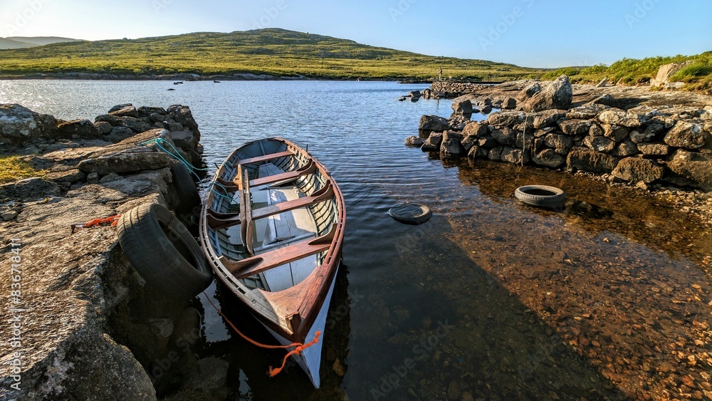 Old wooden fishing boat in lake by Fisherman's hut with mountains in background at Connemara, Galway, Ireland