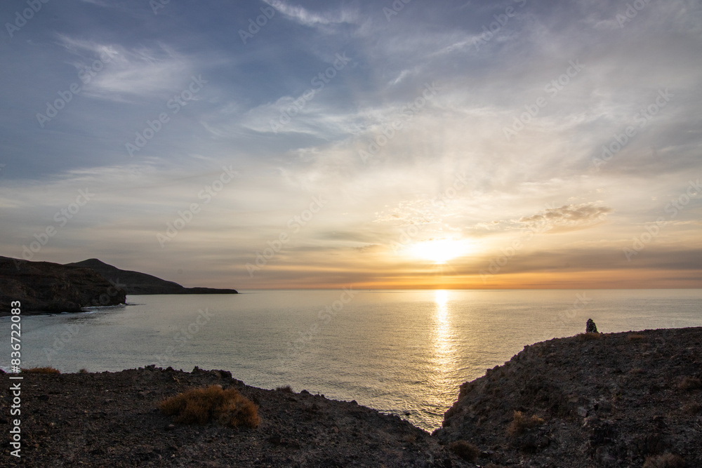 Sunrise with sea view in a secluded bay. rocky coast in warm colors. Landscape with a lava stone beach at Tarajalejo on Fuerteventura, Canary Islands, Spain. Sunrise with sea view in a secluded bay. rocky coast in warm colors. Landscape with a lava stone beach at Tarajalejo on Fuerteventura, Canary Islands, Spain.