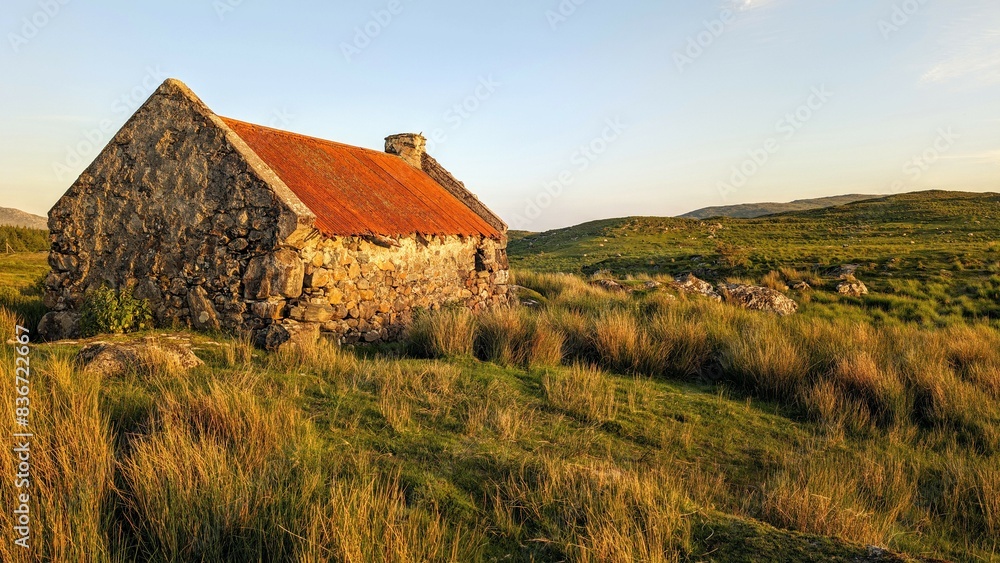 Beautiful landscape scenery with old rusty tin roof cottage on green hill at Connemara National park in County Galway, Ireland