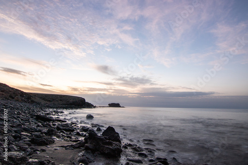 Sunrise with a sea view on a rocky coast in warm colors. Landscape with a lava stone beach at Tarajalejo on Fuerteventura, Canary Islands, Spain. photo