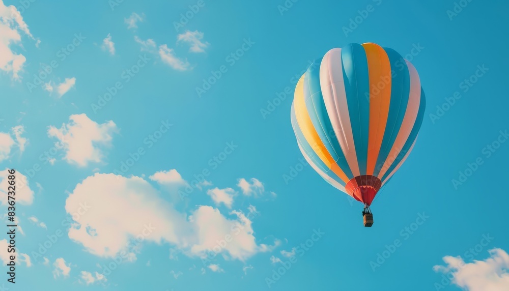 Naklejka premium Vibrant Journey: A Colorful Hot Air Balloon Soaring Through the Blue Skies