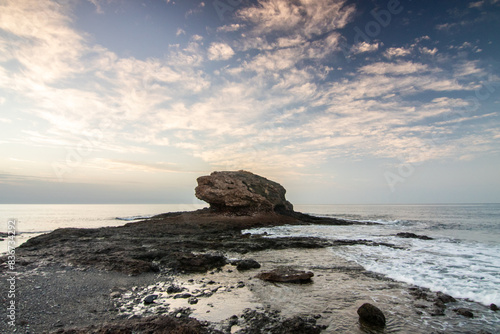 Sunrise with a sea view on a rocky coast in warm colors. Landscape with a lava stone beach at Tarajalejo on Fuerteventura, Canary Islands, Spain. photo