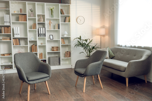 Psychologists office with cozy chairs sofa and shelves with books