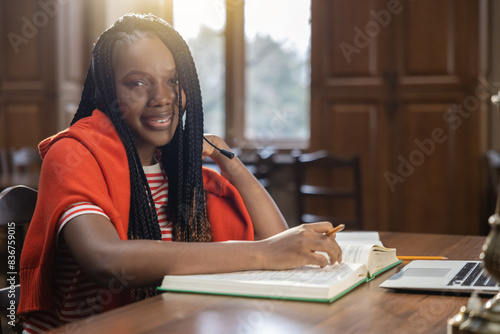 Cute african american young woman sitting at the table in the library