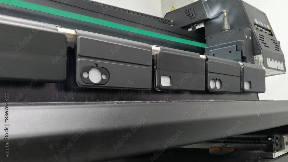 A modern digital large-format UV printer prints images on smartphone cases. UV pinning is the process of applying a dose of low intensity ultraviolet light to a UV curable ink A modern digital large-format UV printer prints images on smartphone cases. UV pinning is the process of applying a dose of low intensity ultraviolet light to a UV curable ink