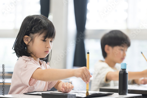 Fotografía 明るい小学校の教室で習字を教わる小学生の女の子