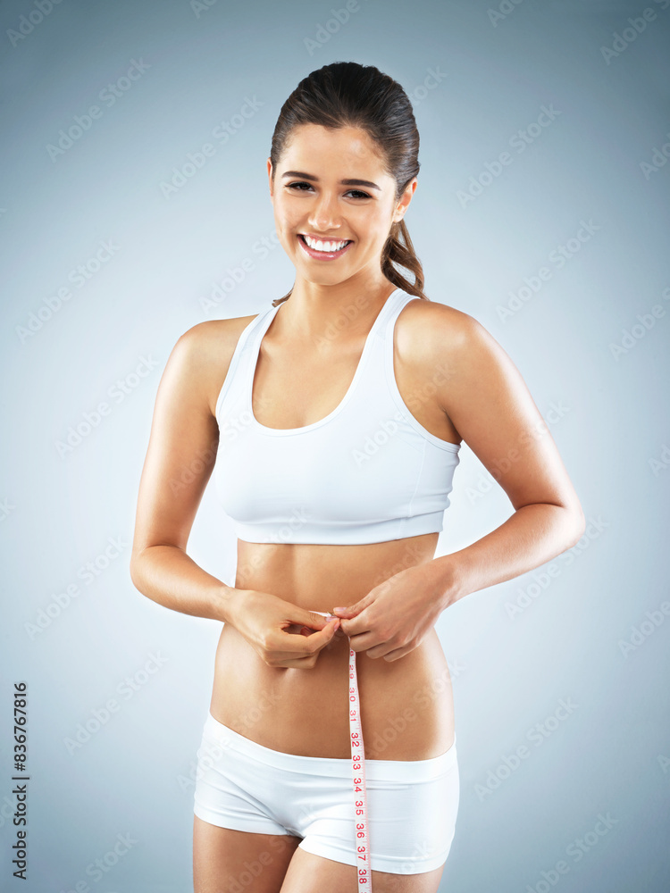 Stomach, portrait or happy woman with tape measure for fitness, body progress or workout in studio. Girl, smile or proud athlete with exercise, wellness or training to lose weight on blue background Stomach, portrait or happy woman with tape measure for fitness, body progress or workout in studio. Girl, smile or proud athlete with exercise, wellness or training to lose weight on blue background