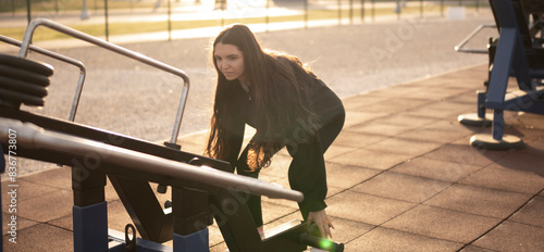 Woman Performing Deadlift Exercise at Outdoor Gym During Golden Hour