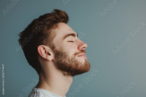 A close up of a man with beard and closed eyes looking to a side