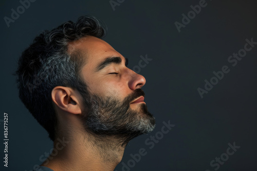 A close up of a man with beard and closed eyes looking to a side